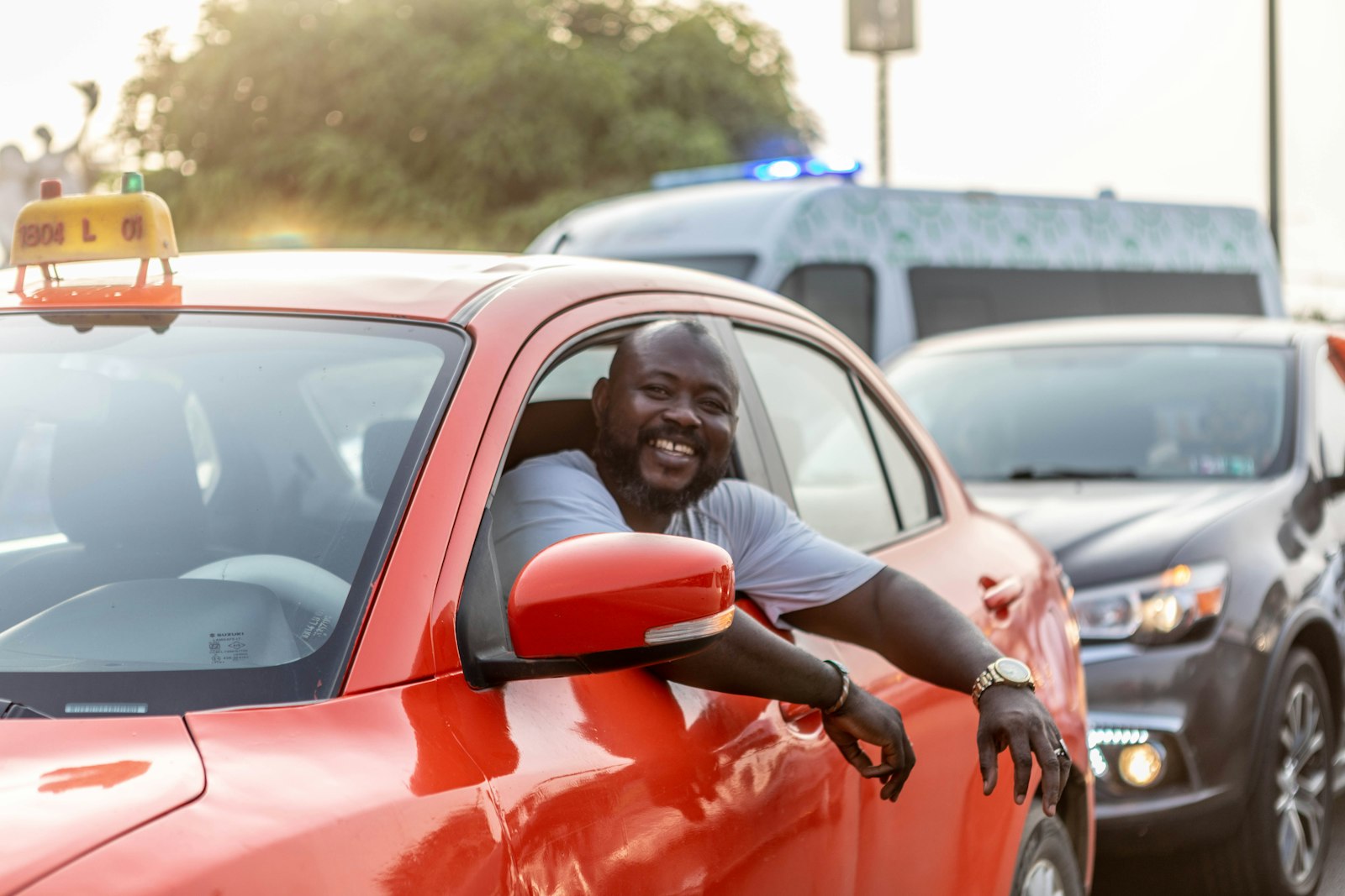 A smiling Transix driver-partner leaning out of his taxi